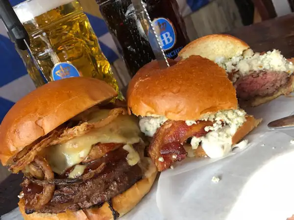 Several hamburgers with different toppings, including cheese, bacon and onion rings. 