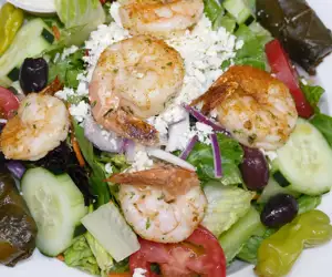 Garden salad topped with sauteed shrimp. 