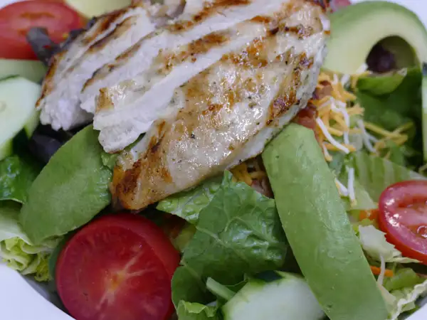 Salad topped with grilled chicken breast. 
