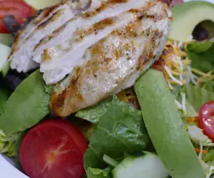 Salad topped with grilled chicken breast. 