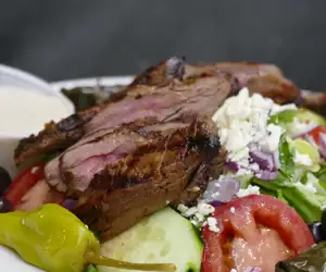 Salad with grilled, sliced steak on top. 